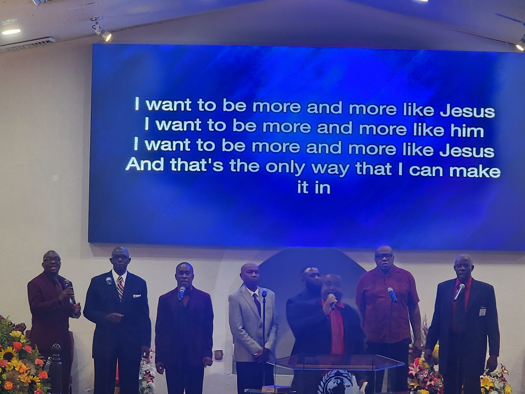 Men's choir singing with lyrics on screen at Ingathering.