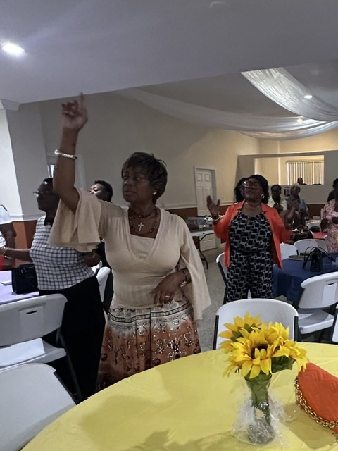 A guest lifting a hand in worship at the Know Your Neighbor Prayer Breakfast.