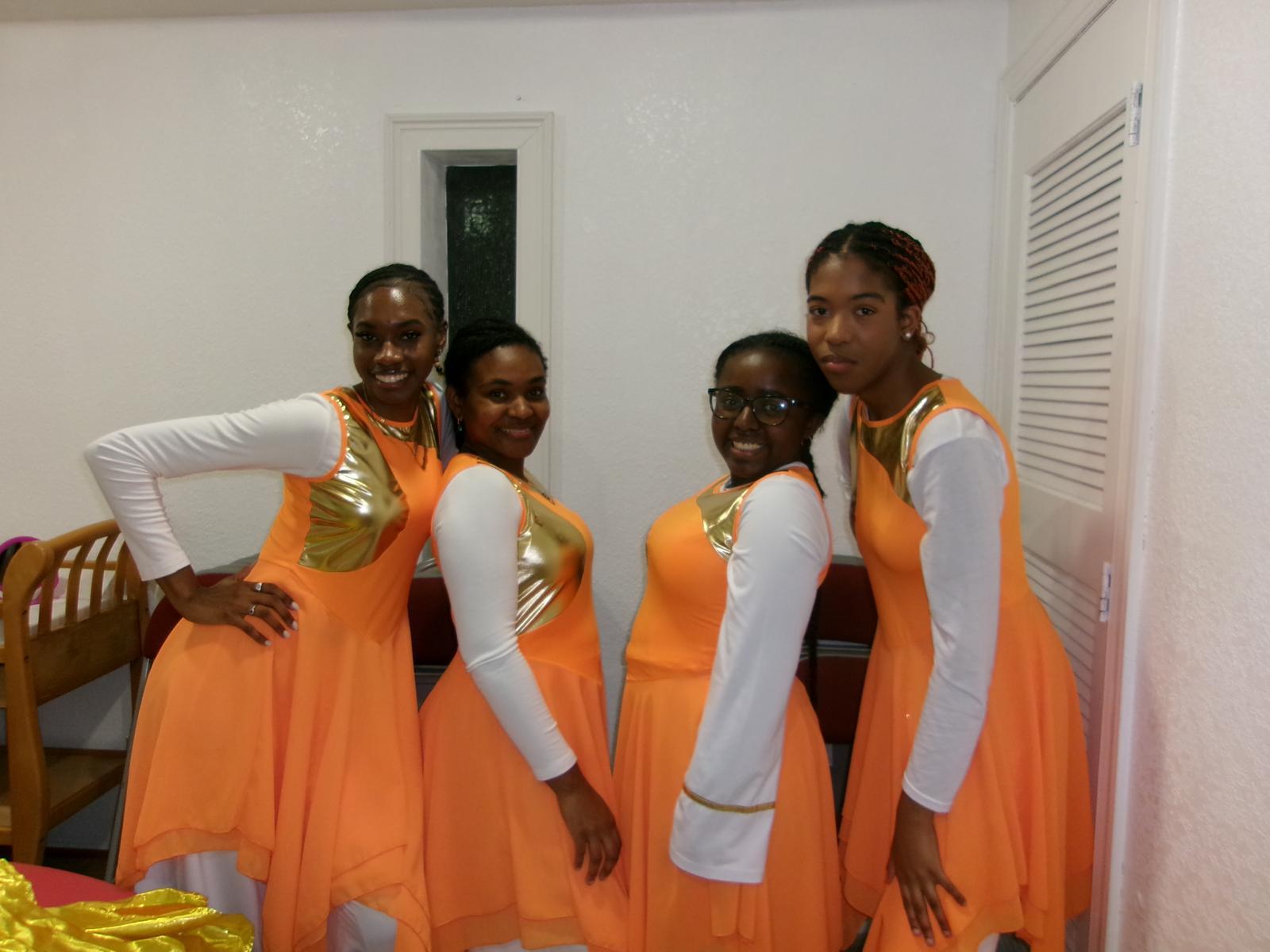 Youth Ministry members in matching orange and gold performance outfits.